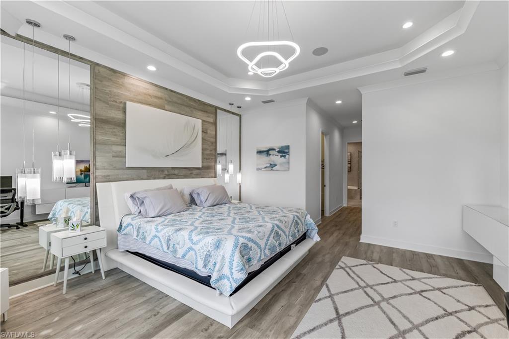 4410 Caldera Circle Naples, FL 34119 - Photo 22 of 30 a bedroom with a large bed and a chandelier