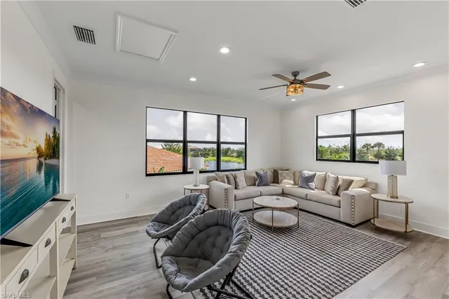 a living room with furniture a flat screen tv and a large window