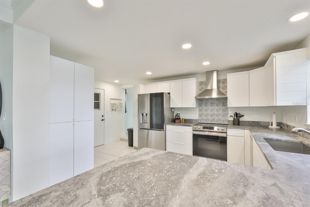 387 12th Avenue Indian Rocks Beach, FL 33785 - Photo 28 of 44 a open kitchen with stainless steel appliances granite countertop a refrigerator stove top oven and sink
