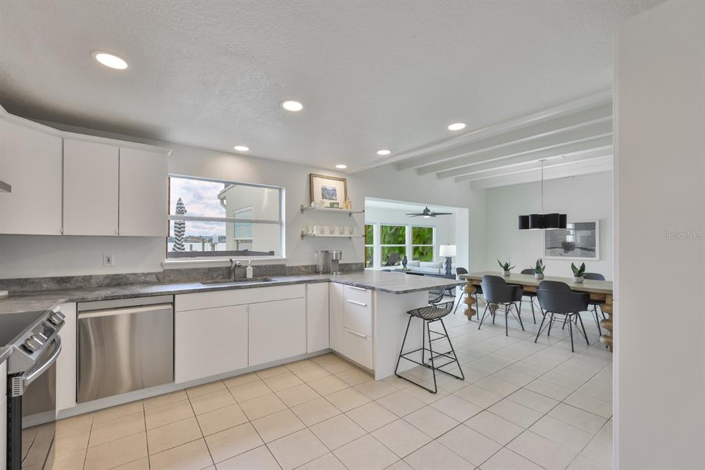 387 12th Avenue Indian Rocks Beach, FL 33785 - Photo 30 of 44 a kitchen with white cabinets a sink dining table and chairs