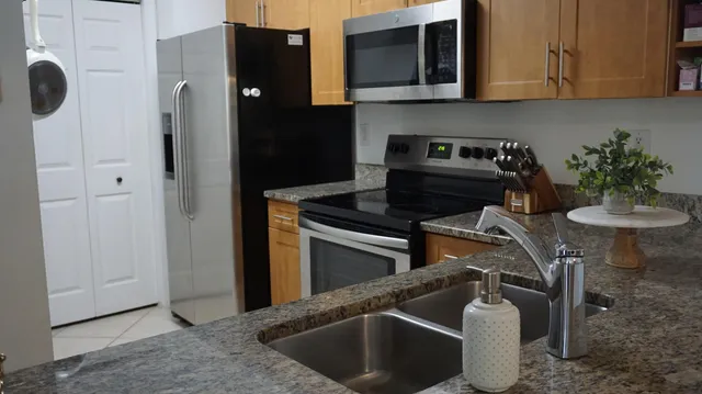 a kitchen with granite countertop stainless steel appliances stove microwave and cabinets