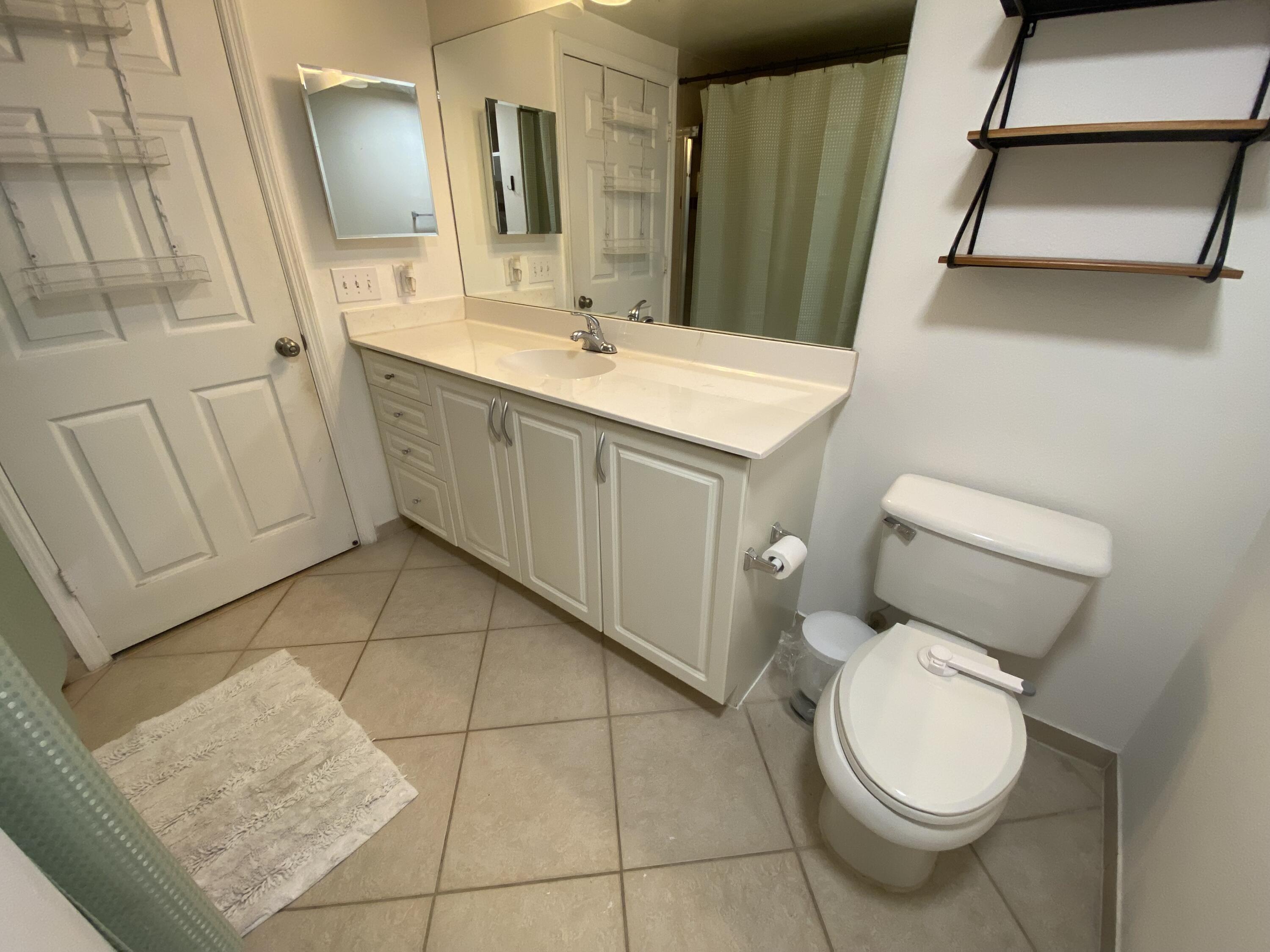 6511 Emerald Dunes Drive, Unit 208 West Palm Beach, FL 33411 - Photo 27 of 51 a bathroom with a toilet sink and mirror