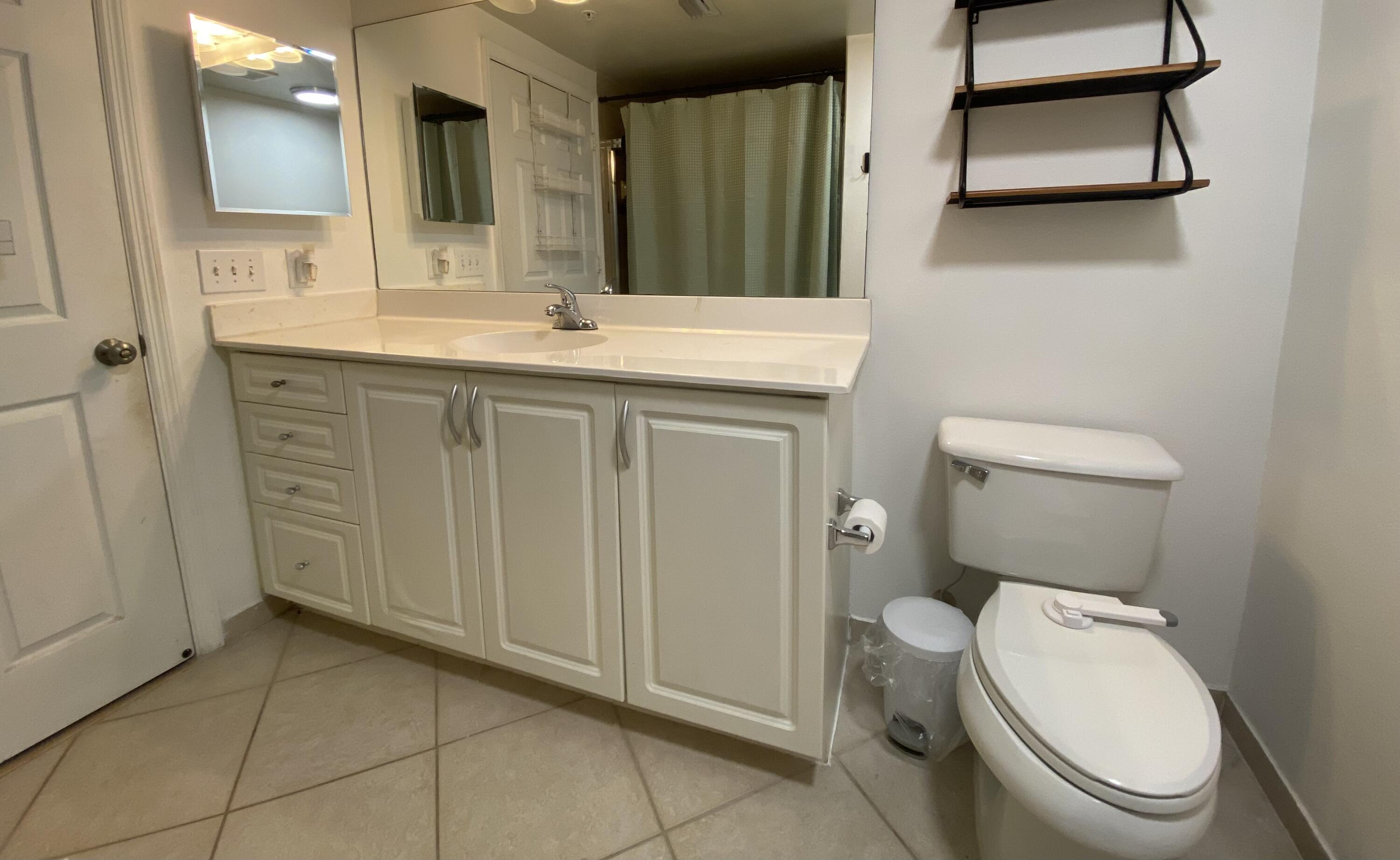 6511 Emerald Dunes Drive, Unit 208 West Palm Beach, FL 33411 - Photo 29 of 51 a bathroom with a toilet a sink and mirror