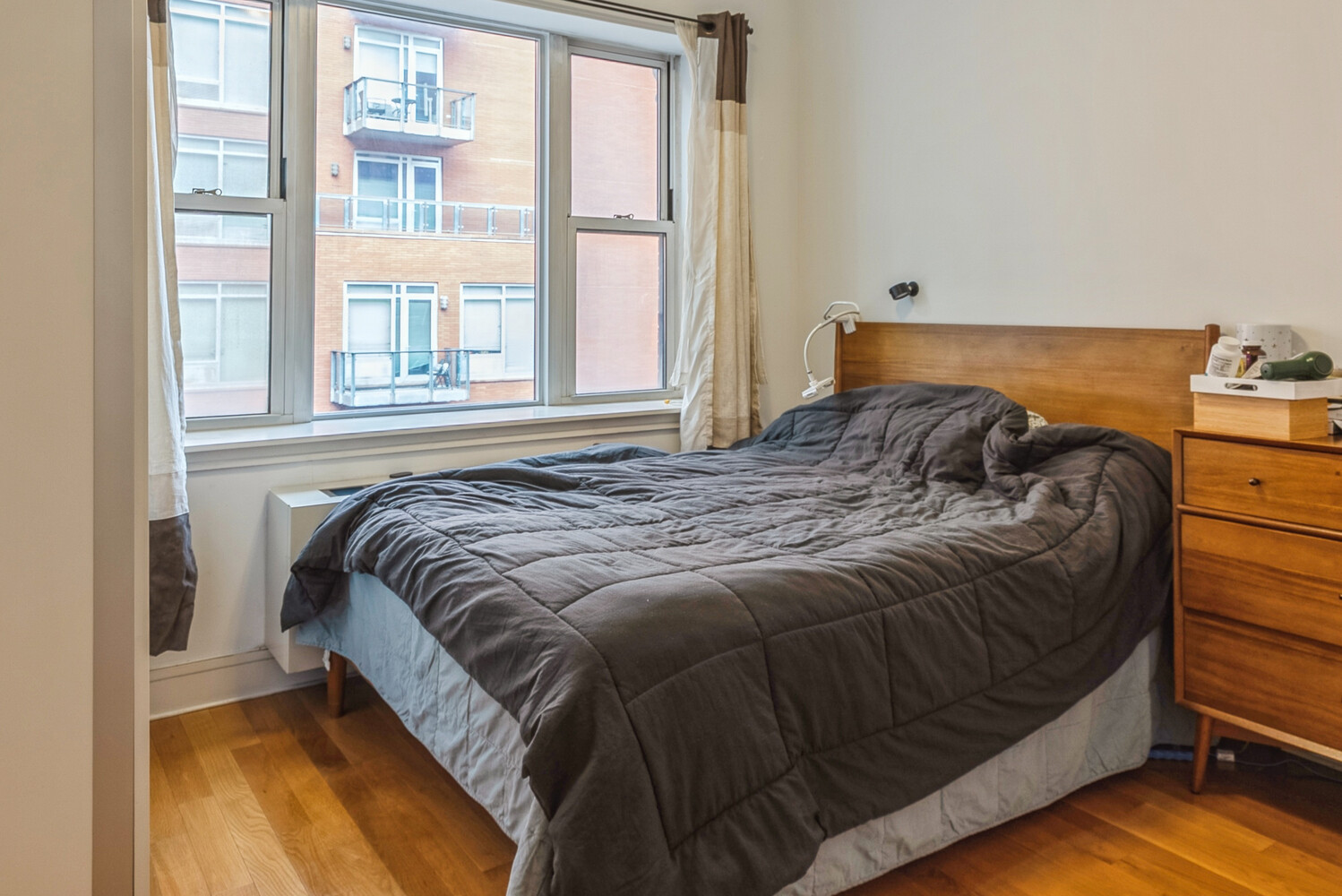 41-26 27th Street, Unit 8B Queens, NY 11101 - Photo 4 of 11 a bed sitting in a bedroom next to a window