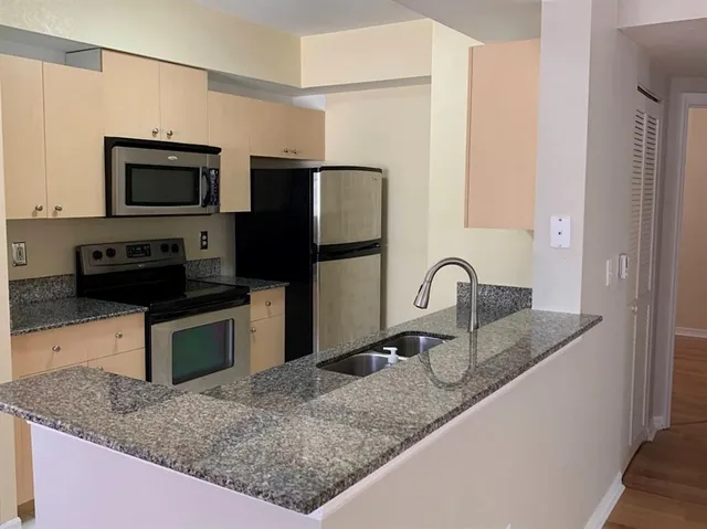 a kitchen with stainless steel appliances granite countertop a sink a stove and microwave