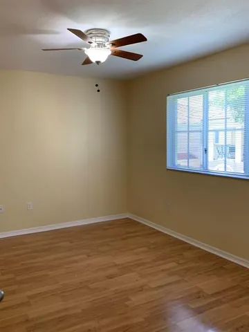 a view of a room with wooden floor chandelier fan and windows