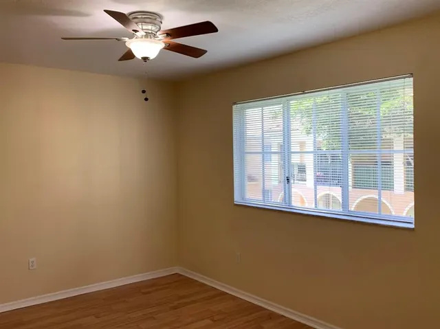 a view of empty room with wooden floor and fan