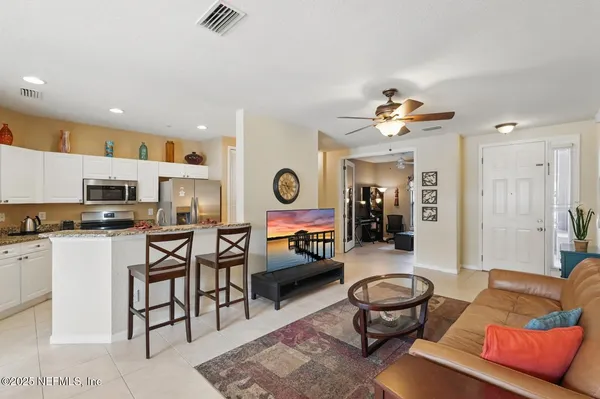 a living room with stainless steel appliances furniture a rug and a view of kitchen