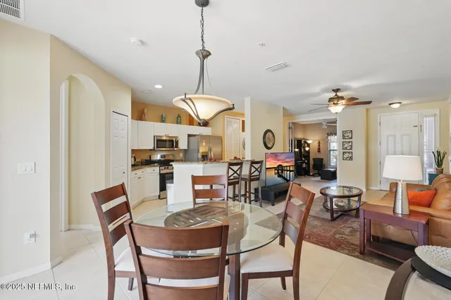 a kitchen with stainless steel appliances kitchen island granite countertop a refrigerator a stove a sink and white cabinets with wooden floor