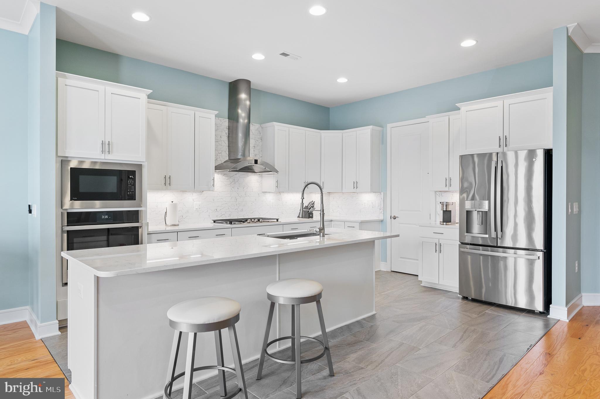 42791 Macbeth Terrace Ashburn, VA 20148 - Photo 5 of 63 a kitchen with kitchen island white cabinets and stainless steel appliances