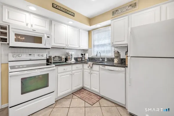 a kitchen with stainless steel appliances granite countertop white cabinets sink and a refrigerator
