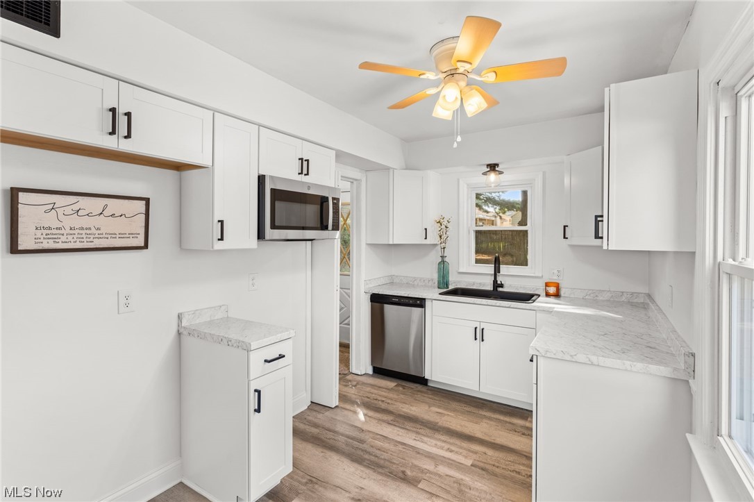 898 Reed Avenue Akron, OH 44306 - Photo 11 of 26 Kitchen with light countertops, appliances with stainless steel finishes, white cabinetry, light hardwood flooring, and ceiling fan
