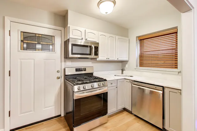 a kitchen with white cabinets and stainless steel appliances