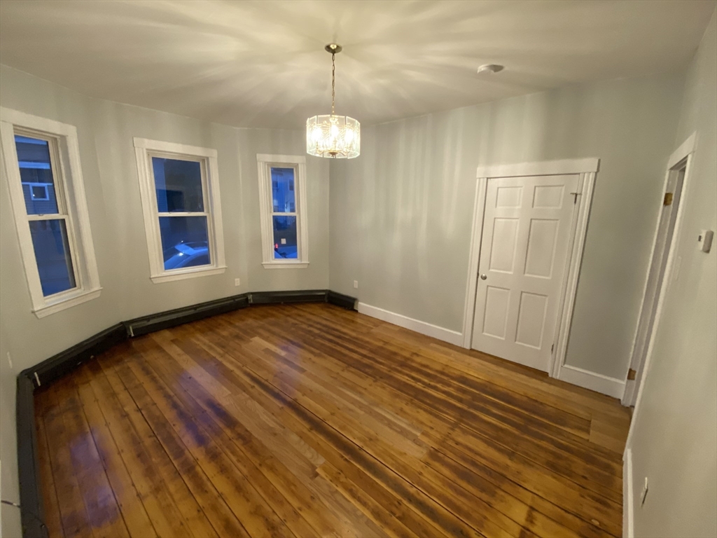 a view of an empty room with wooden floor and window