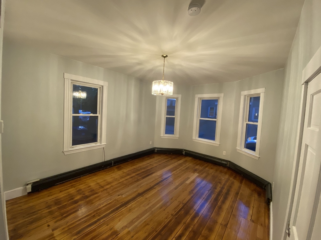 63 Marshfield Street, Unit 1 Boston, MA 02119 - Photo 2 of 26 a view of an empty room with wooden floor and a window