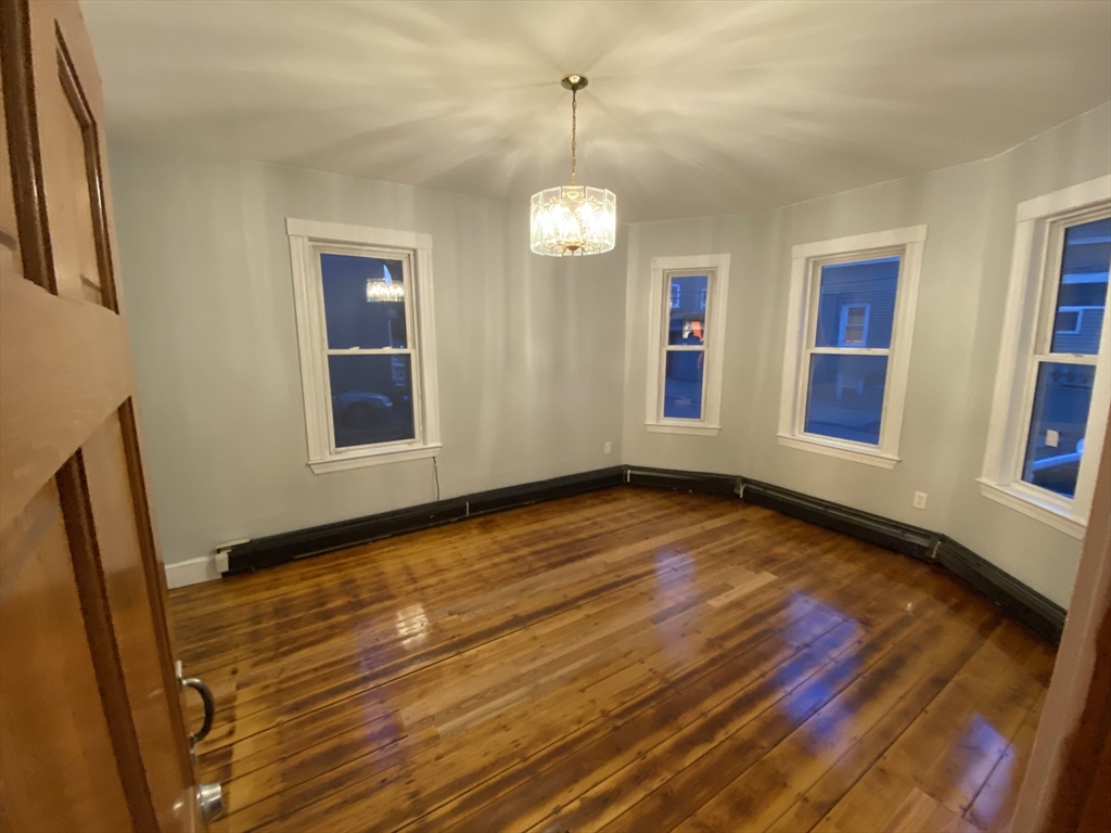 63 Marshfield Street, Unit 1 Boston, MA 02119 - Photo 3 of 26 a view of an empty room with wooden floor and a window