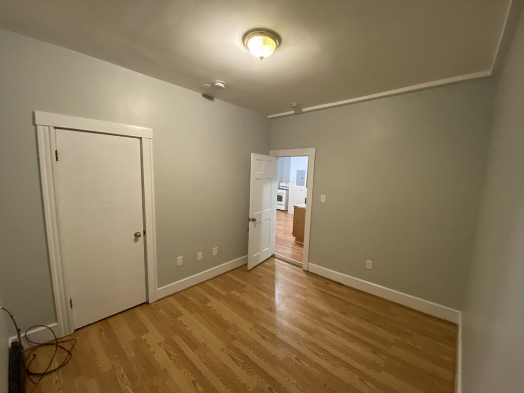 63 Marshfield Street, Unit 1 Boston, MA 02119 - Photo 7 of 26 an empty room with wooden floor and windows