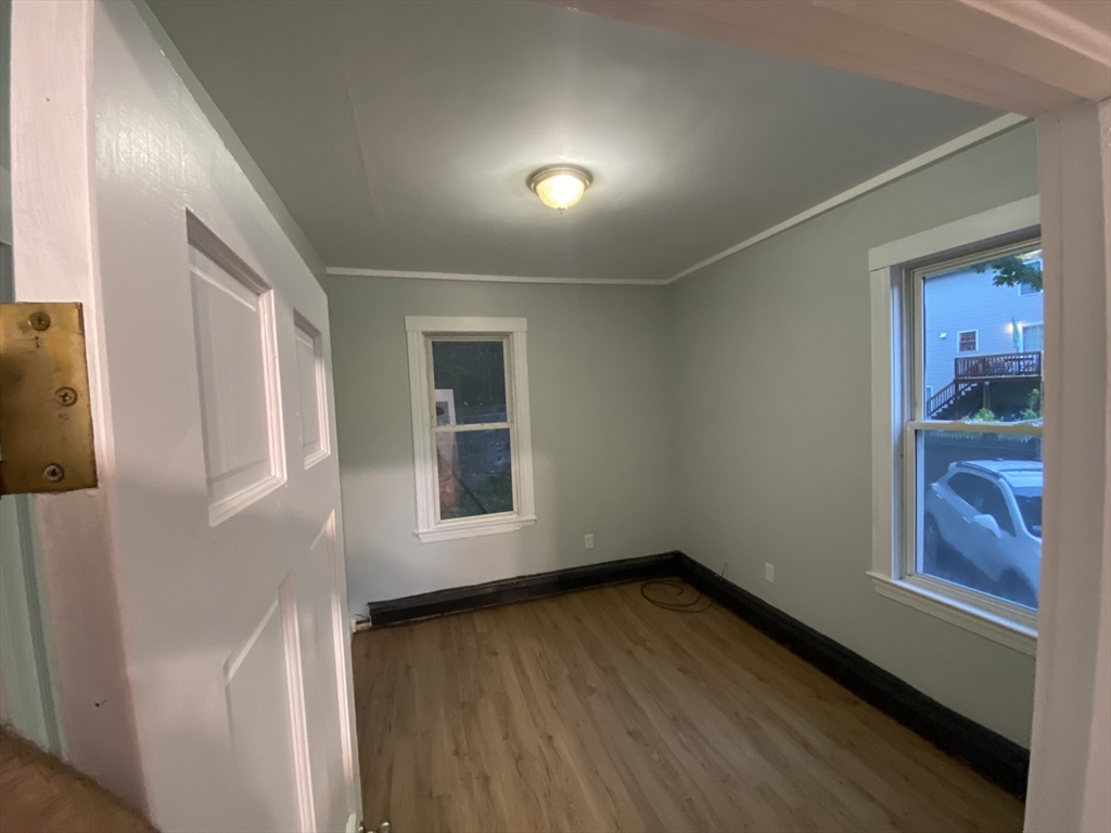 63 Marshfield Street, Unit 1 Boston, MA 02119 - Photo 8 of 26 an empty room with wooden floor and windows