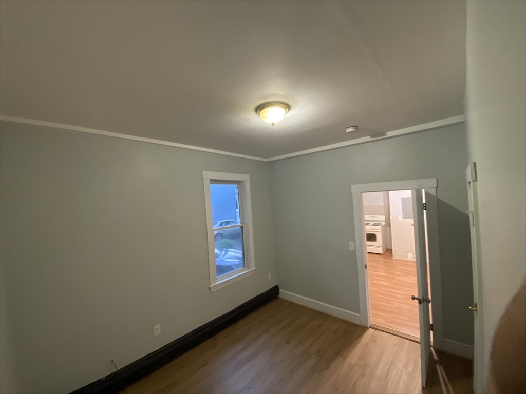 63 Marshfield Street, Unit 1 Boston, MA 02119 - Photo 9 of 26 an empty room with wooden floor and windows