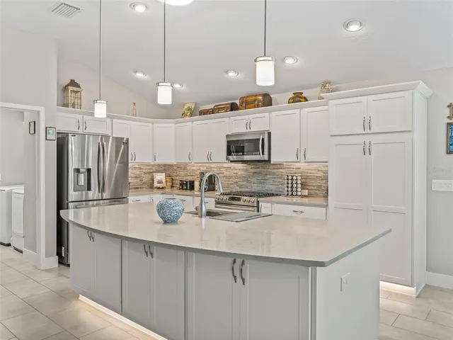 a kitchen with kitchen island granite countertop a sink stainless steel appliances and cabinets