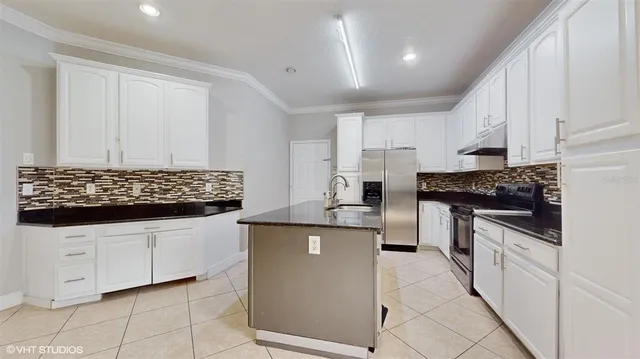 a kitchen with stainless steel appliances a stove a sink and white cabinets