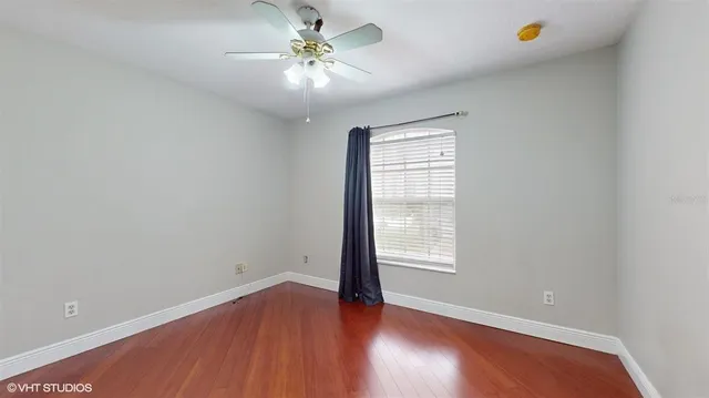 an empty room with wooden floor and window