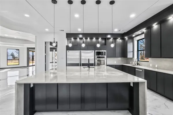 a large kitchen with a large counter top a sink a stove and cabinets