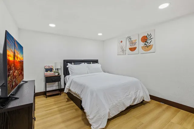 a spacious bedroom with a bed and a painting on the wall