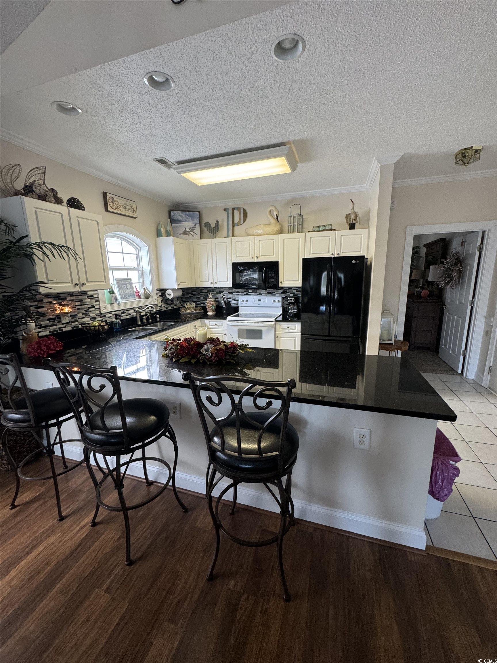 1538 Lanterns Rest Road, Unit 303 Myrtle Beach, SC 29579 - Photo 4 of 23 Kitchen with a kitchen bar, light wood-type floori