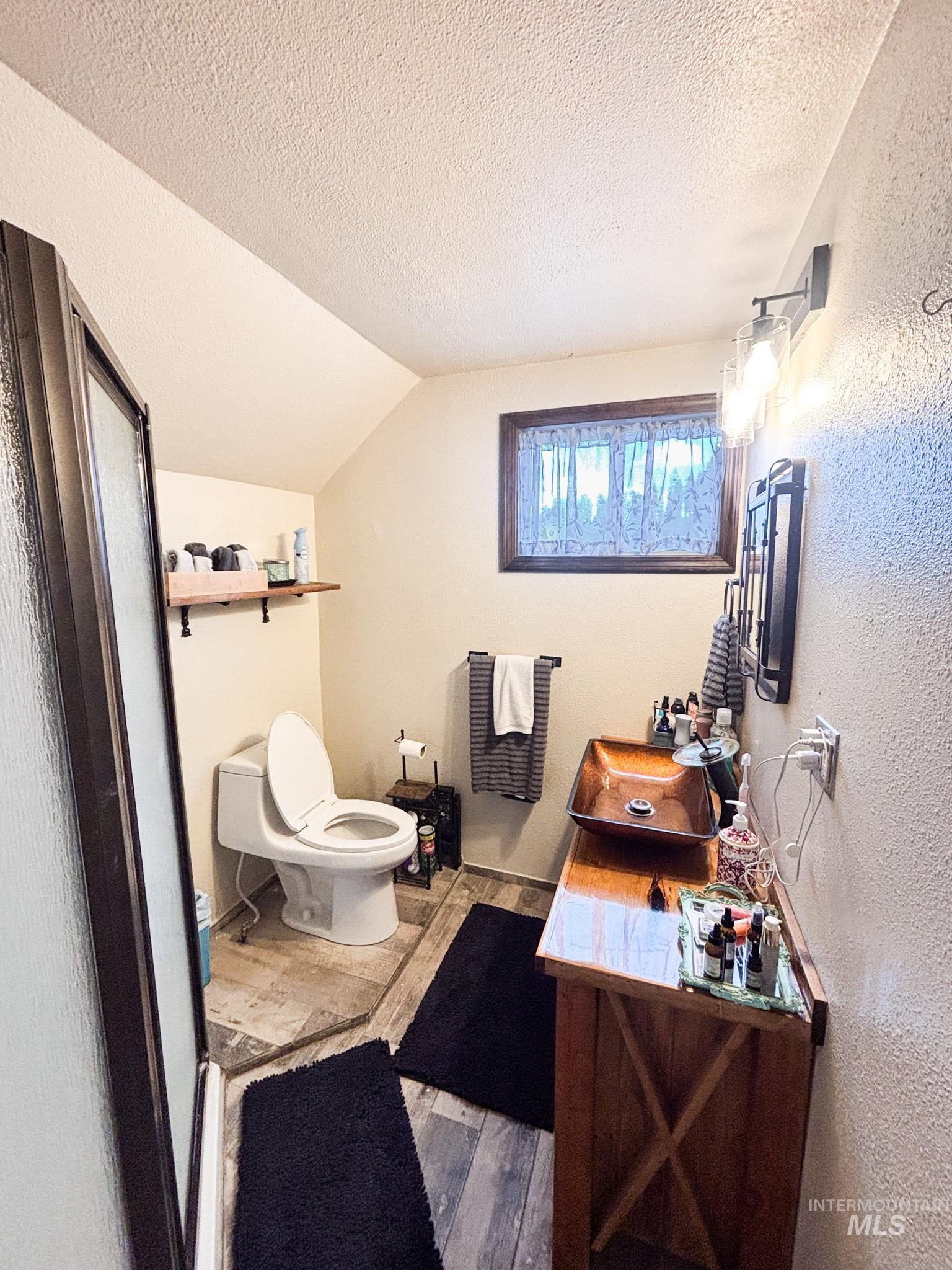 1995 Glenwood Road Kamiah, ID 83536 - Photo 21 of 38 Bathroom featuring a rectangular copper vessel sink, wood-finish vanity, and industrial-style wall sconce