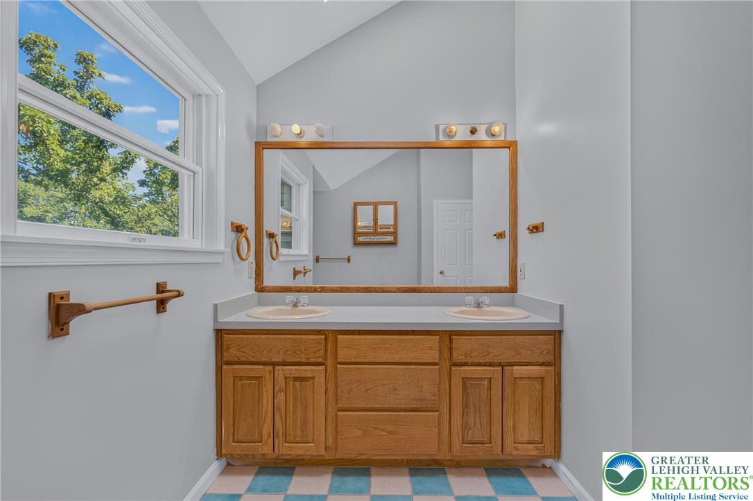 630 Clearfield Road Nazareth, PA 18064 - Photo 58 of 100 High vaulted ceilings and a dual vanity with oak cabinetry anchor this bathroom space.