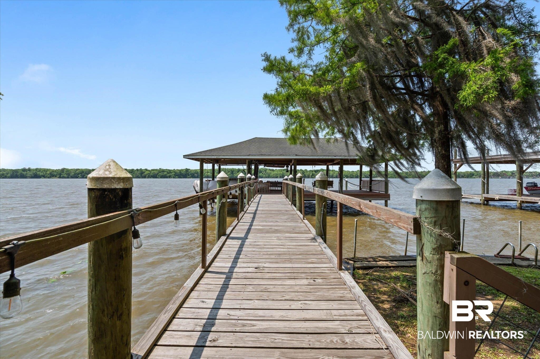 41923 Bayou Road Bay Minette, AL 36507 - Photo 26 of 35 Waterfront wooden dock with a covered boat slip, featuring string lights along the railing
