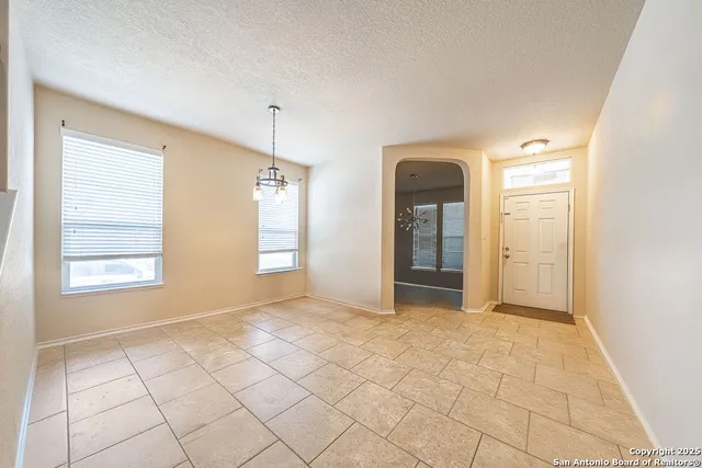 a view of an empty room with window and chandelier fan