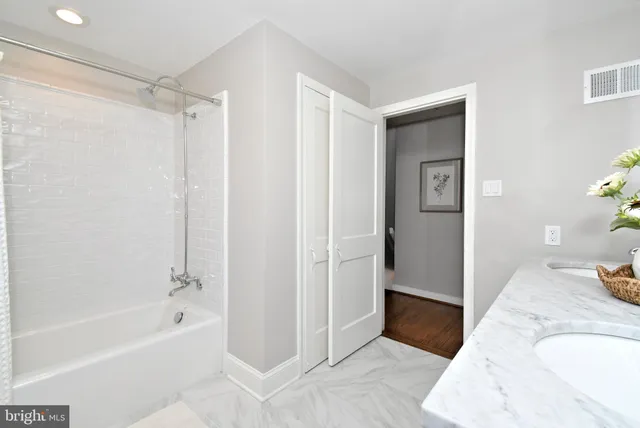 a view of a house with lots of flower plants and large tree