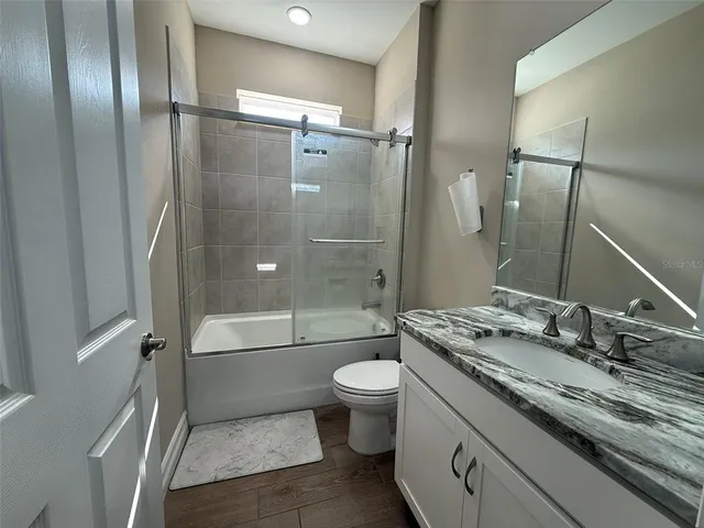 a bathroom with a granite countertop sink toilet and shower