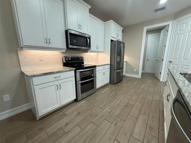 a kitchen with stainless steel appliances granite countertop a stove a sink and a refrigerator