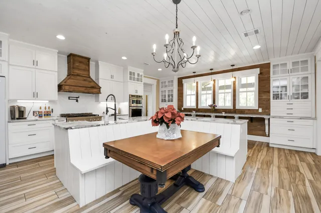 a kitchen with stainless steel appliances granite countertop a stove top oven a sink dishwasher and white cabinets with wooden floor