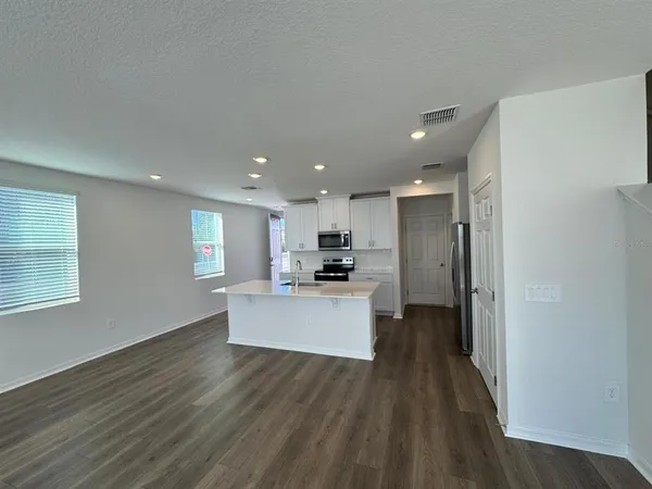 a view of kitchen with kitchen island wooden floor center island and stainless steel appliances