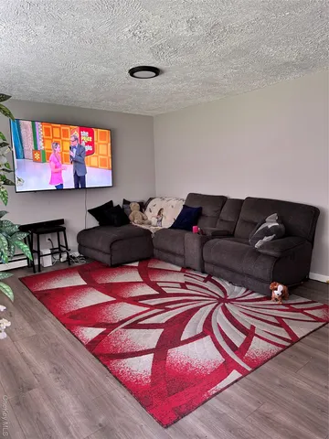 a living room with furniture a flat screen tv and floor to ceiling window