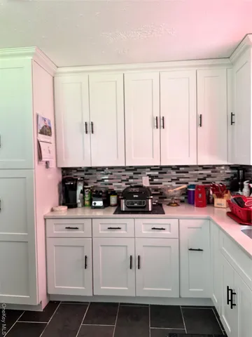 a kitchen with white cabinets and sink
