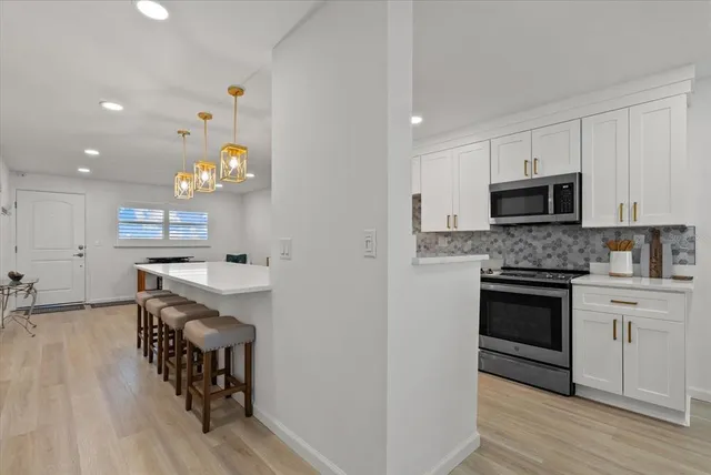 a kitchen with granite countertop a stove top oven a sink dishwasher and a microwave oven with wooden floor