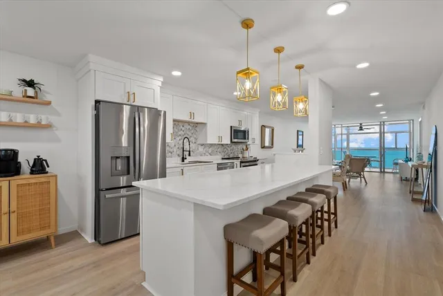 a kitchen with stainless steel appliances a dining table chairs refrigerator and microwave