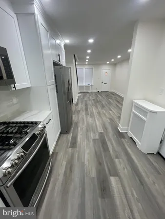 a view of kitchen with refrigerator stove and wooden floor