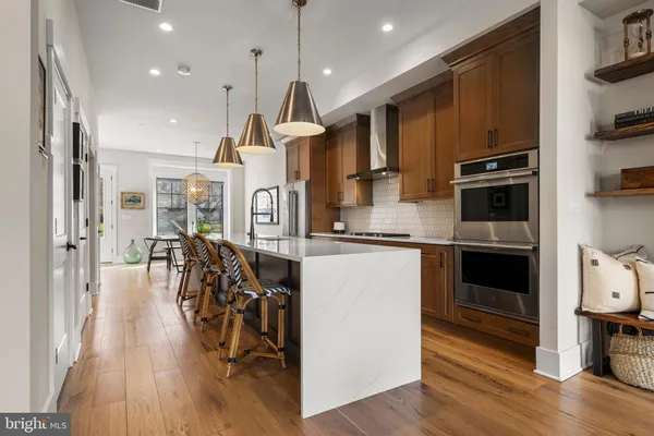 a kitchen with stainless steel appliances granite countertop a refrigerator a oven a stove and a wooden floors