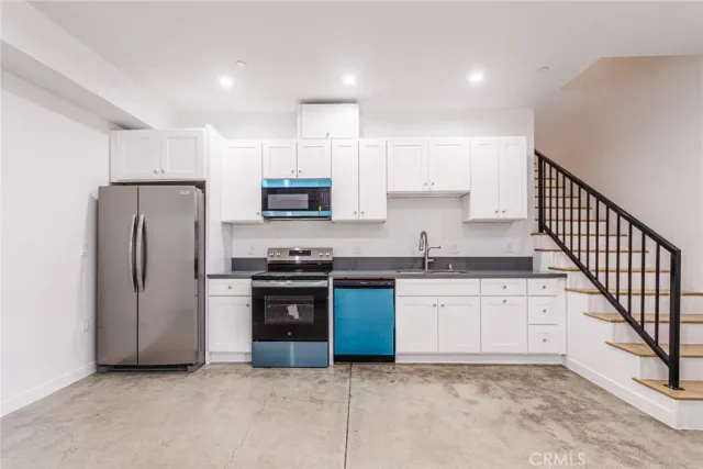 a kitchen with stainless steel appliances granite countertop a refrigerator a stove a sink and a microwave