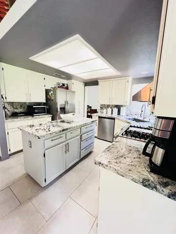 a kitchen with stainless steel appliances kitchen island granite countertop a sink stove and refrigerator