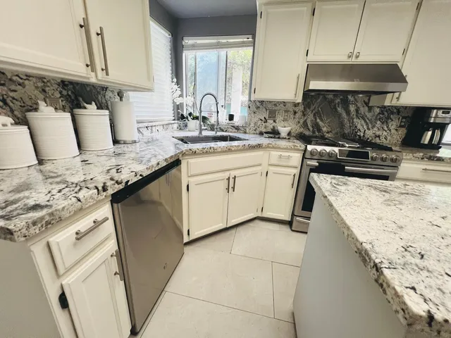 a kitchen with granite countertop a sink a stove and cabinets