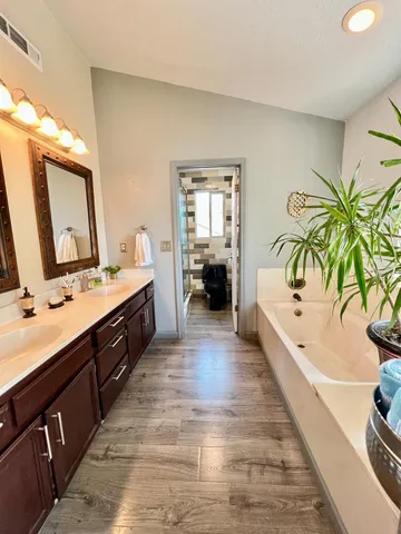 a spacious bathroom with a double vanity sink a mirror and a bathtub