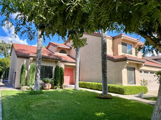 a front view of a house with a garden and tree
