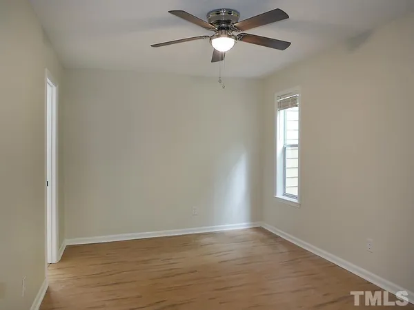 an empty room with wooden floor fan and windows